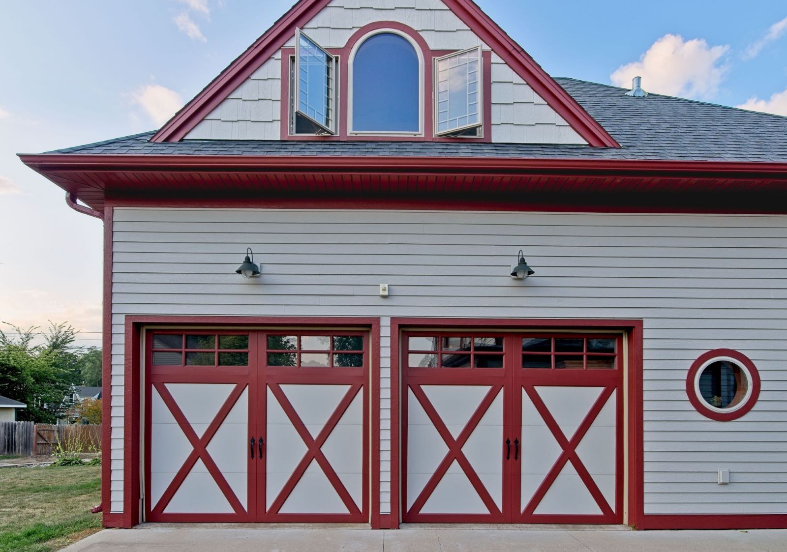 Straight-on front view of the detached carriage house garage at 504 W. Cavour Ave, showcasing custom cross-buck doors, red trim, and an upper arched window peak.