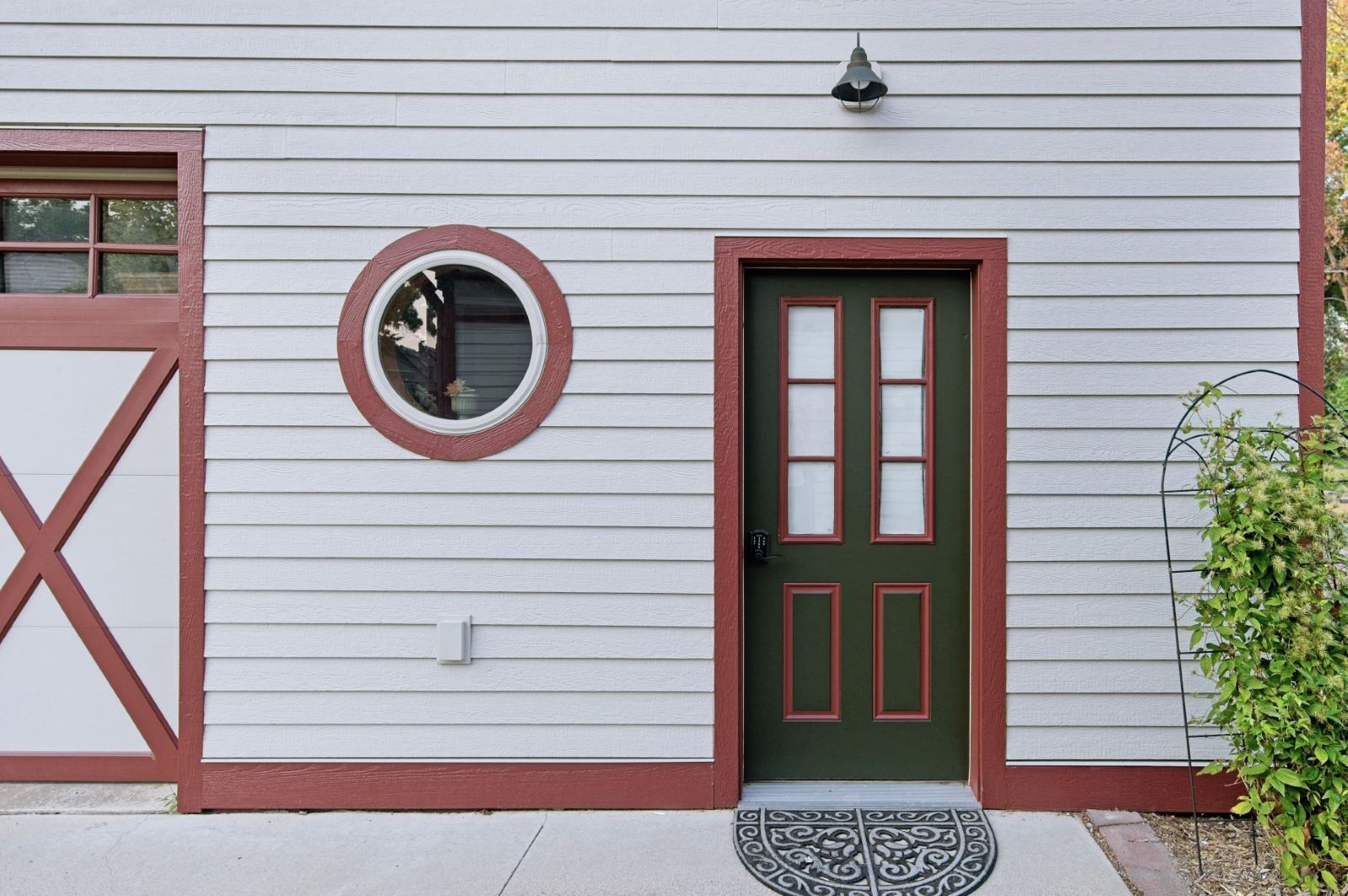 Close-up of the pedestrian entry door and circular porthole window on the freshly painted carriage house garage at 504 W. Cavour Ave, Fergus Falls, Minnesota.