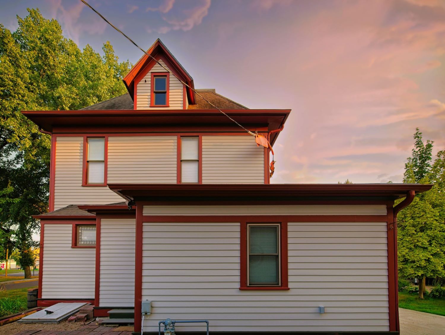 Rear exterior view of the historic 1899 home at 504 W. Cavour Ave in Fergus Falls, Minnesota, showcasing a freshly painted single-story extension, upper levels, and attic dormer.