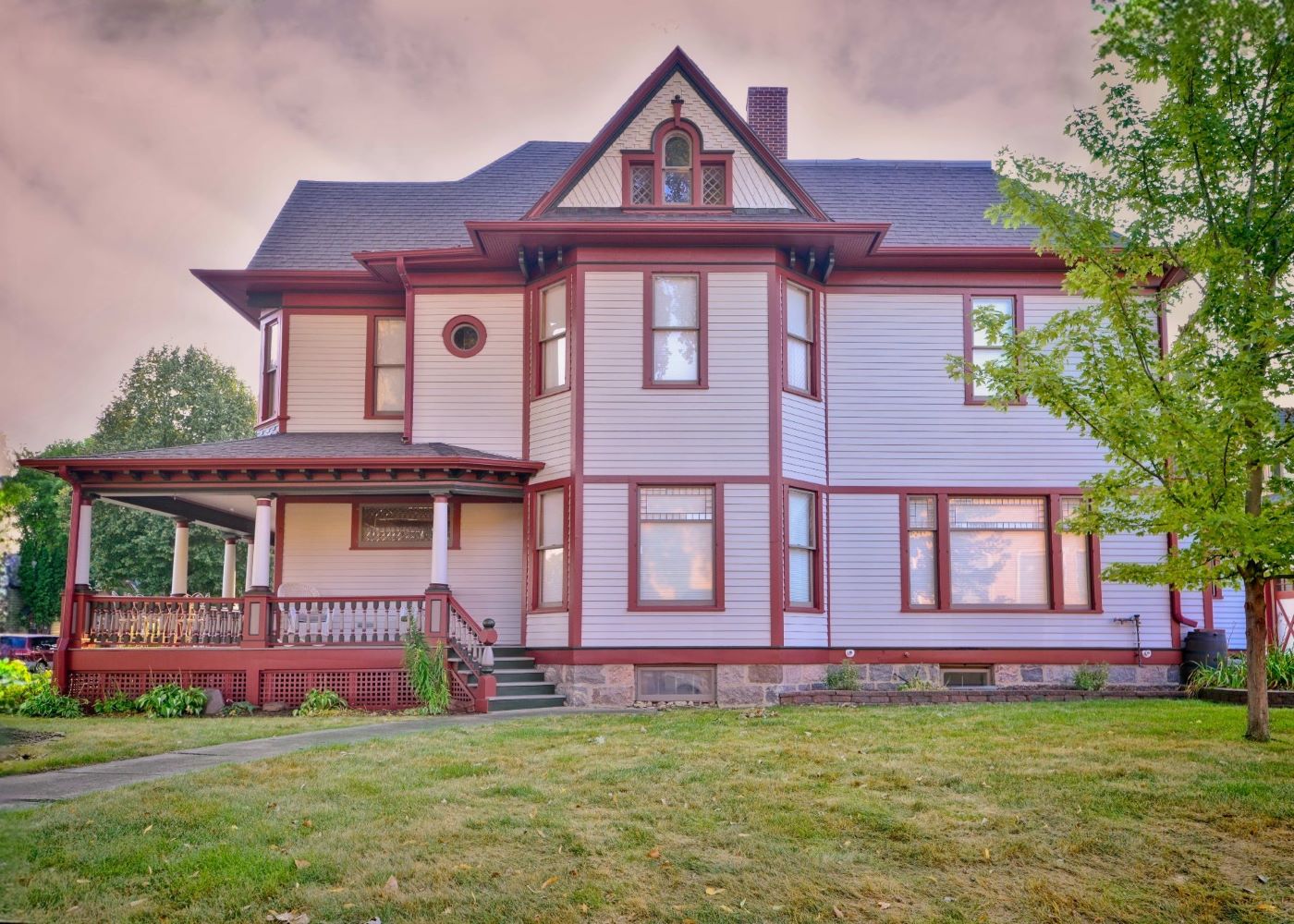 Full side exterior view of the historic 1899 home at 504 W. Cavour Ave in Fergus Falls, Minnesota, showcasing a new light gray and deep red paint job by Big Boys Painting.
