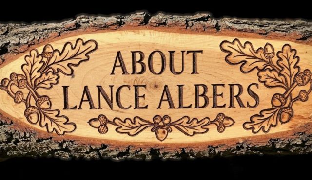 An elongated, rustic wood slab sign with thick tree bark borders, featuring chiseled oak leaf branches and acorns framing the text "ABOUT LANCE ALBERS".