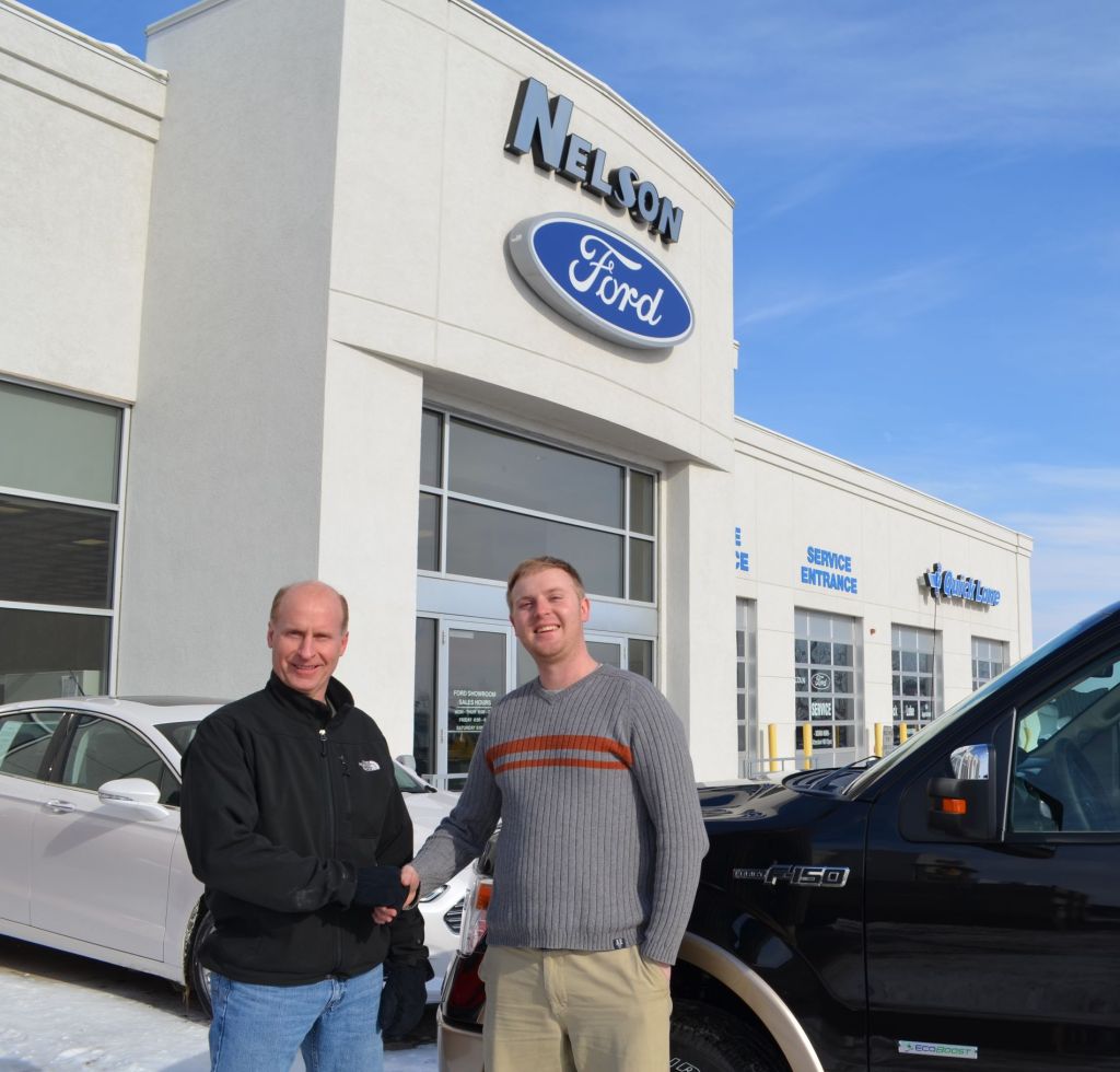Alex Nelson shaking hands with a man outside Nelson Ford dealership next to a black Ford F-150 on February 8, 2014.
