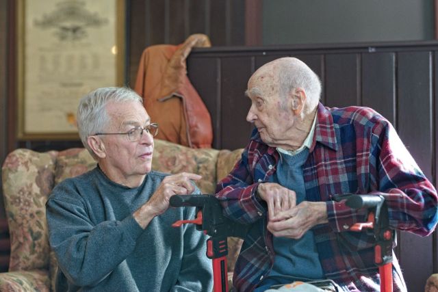 Centenarian Roger Thompson conversing with David Wass at his 100th birthday party in Underwood, Minnesota, photographed by Lance Albers.