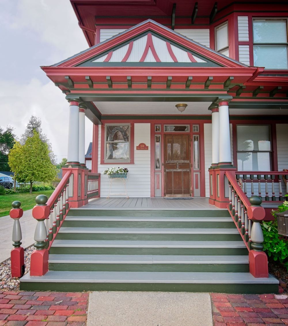 Symmetrical front entryway and wide steps of the historic 1899 home at 504 W. Cavour Ave in Fergus Falls, Minnesota, showcasing red and dark green painted trim by Big Boys Painting.