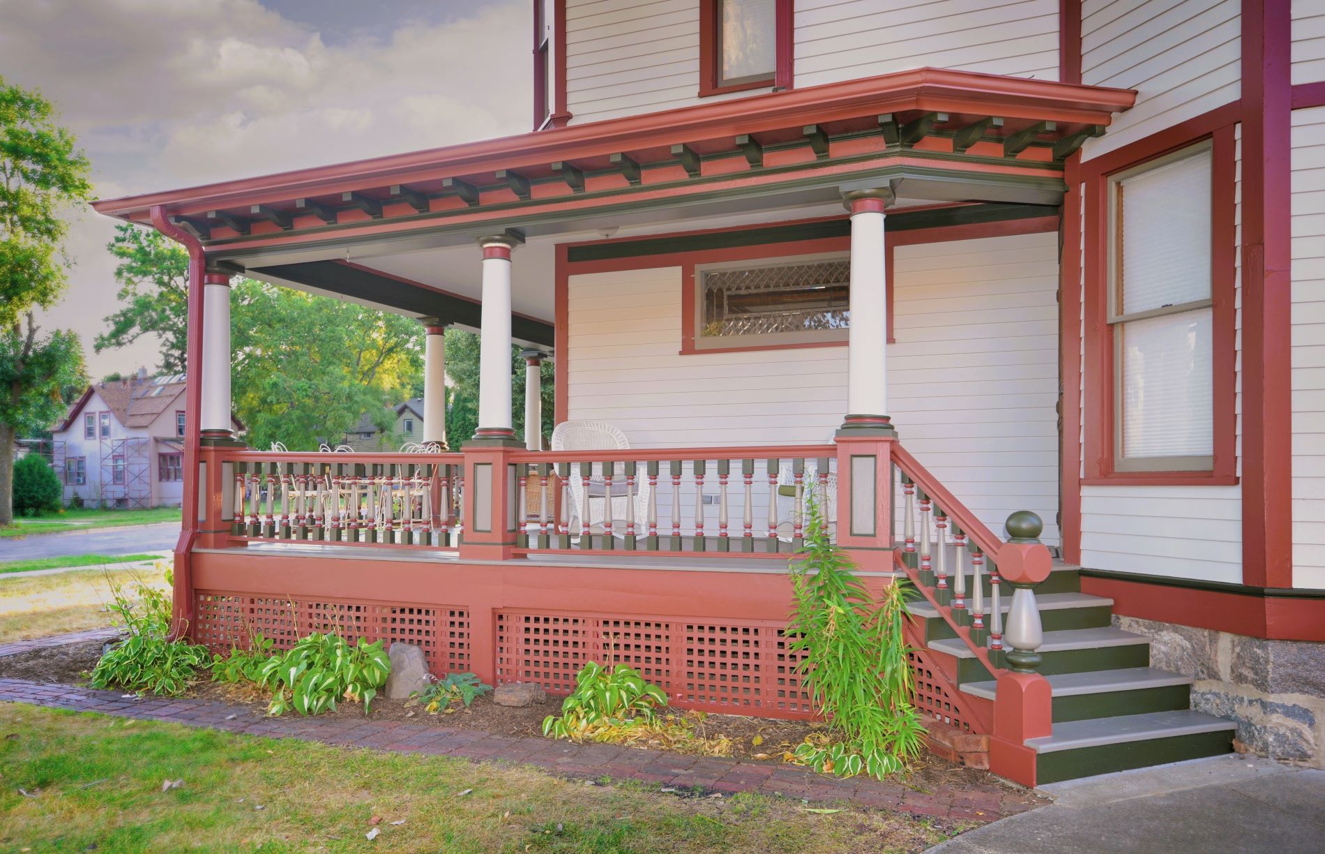 Front covered porch of the historic 1899 home at 504 W. Cavour Ave in Fergus Falls, Minnesota, showcasing red trim, gray steps, and white columns after a professional repainting by Big Boys Painting of Fergus Falls.