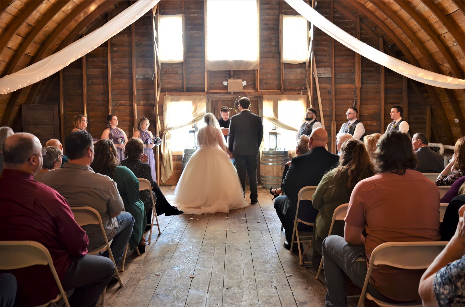 A bride and groom holding hands during their wedding ceremony inside a rustic wooden barn venue in Dunvilla, Minnesota.