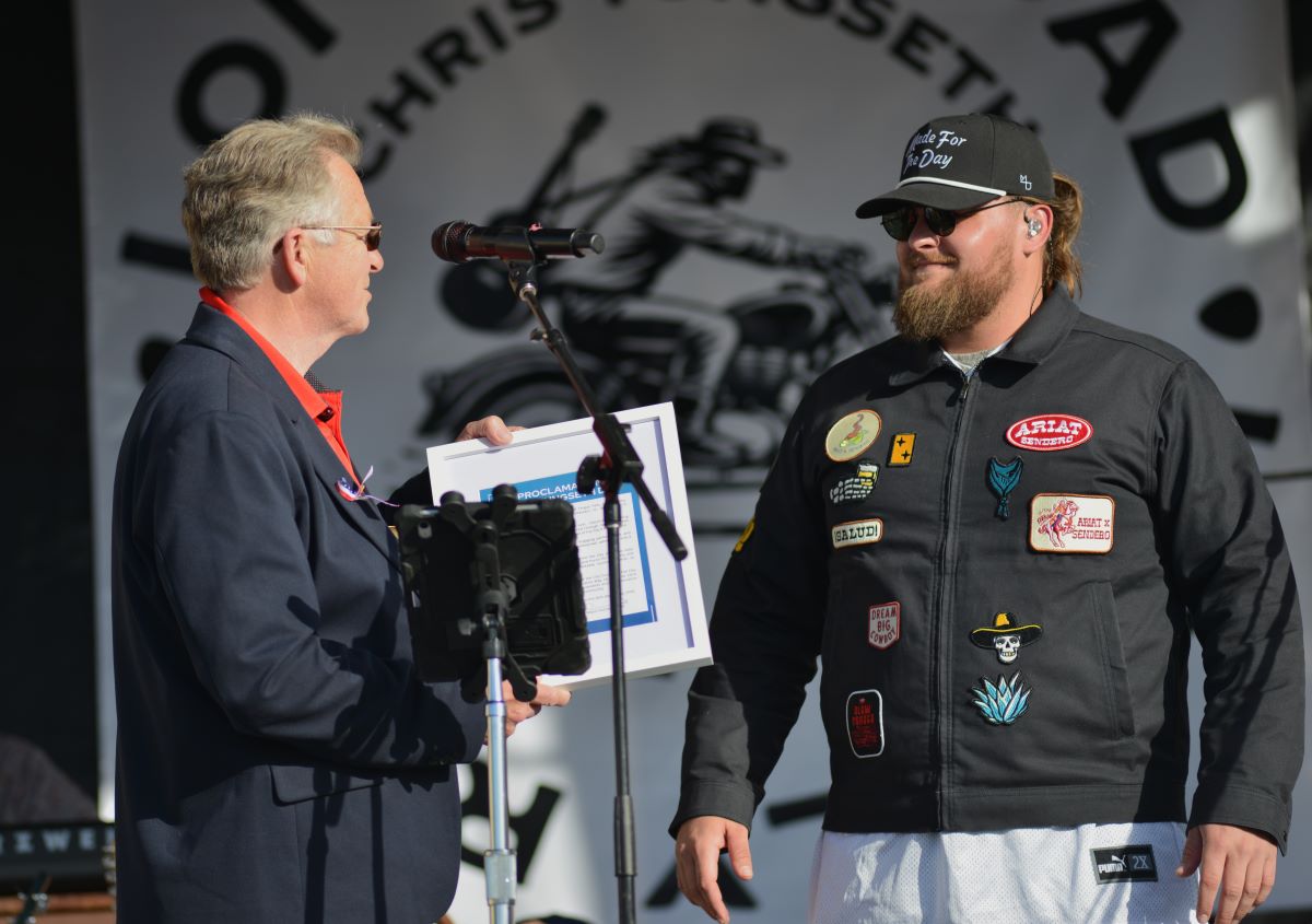Mayor Anthony Hicks comes on stage to present a framed city proclamation to musician Chris Tungseth in Fergus Falls, Minnesota.