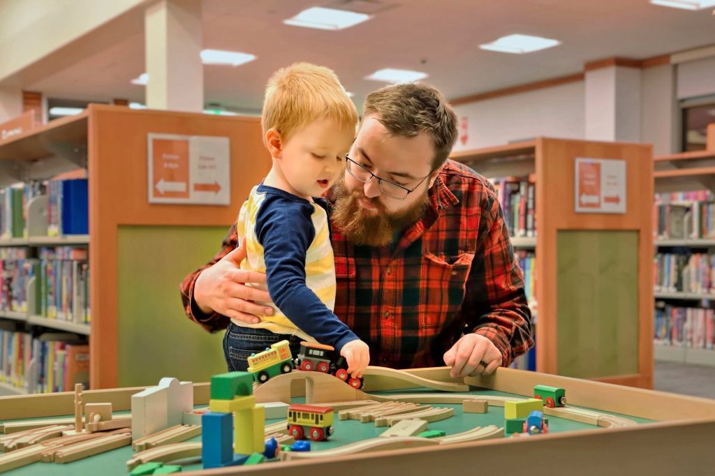 Father and son share a quiet tender moment of playtime together at the Fergus Falls Library in Otter Tail County Minnesota.