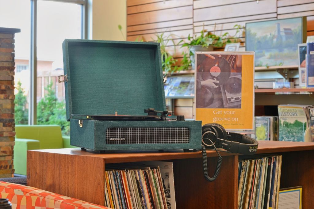 Turntable and headphones setup on a wooden media cabinet at the Fergus Falls Public Library.